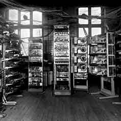 In black and white, the front-ahead view of a room full of data cabinets.