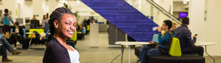 Student sat at desk, smiling at camera