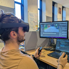 A person experiencing a virtual reality headset in front of a computer monitor